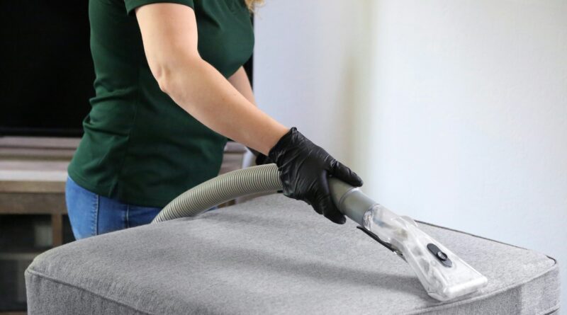 kobieta odkurzająca pufę w salonie